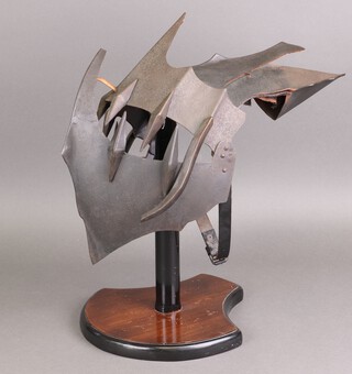 A full size reproduction Uruk Hai Orc helmet from the Lord of the Rings films raised on a wooden stand 