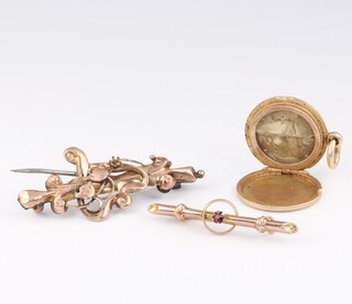 A gold marked 9ct bar brooch set a red stone, a metal and 9ct gold mounted bar brooch and a yellow metal pendant locket, 8.2g gross