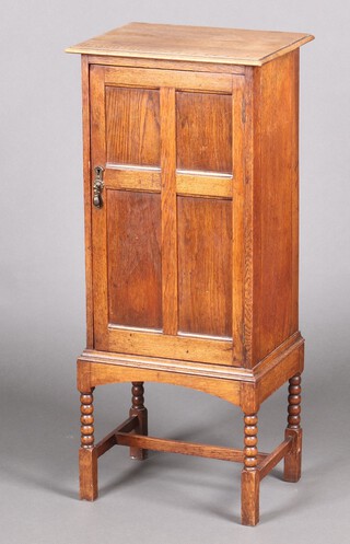 A smoker's oak pedestal cabinet, the interior fitted a pipe rack, shelf and 2 section bottle rack enclosed by a panelled door, raised on spiral turned supports with H framed stretcher, the back marked 932 and with metal label J & S Blower Ltd 95cm h x 41cm w x 32cm d 