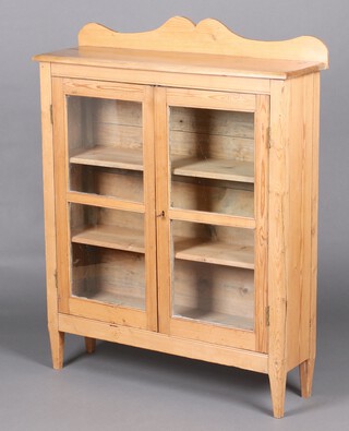 A Victorian pine bookcase/display cabinet with raised back, the interior fitted shelves enclosed by panelled doors, raised on square tapered supports 122cm h x 94cm w x 27cm d 