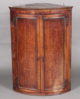 A Georgian oak bow front corner cabinet with moulded cornice and enclosed by panelled doors with H framed metal hinges 105cm h x 74cm wide x 51cm d (together with a receipt dated 8th October 1952 for 22 pounds and 10 shillings)