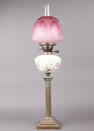 A gilt metal reeded oil lamp with Corinthian column capital and yellow glass reservoir with pink etched glass shade 77cm h 