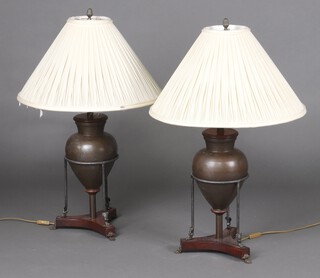 A pair of bronzed metal amphora shaped table lamps, raised on a triform base with paw feet 46cm h 