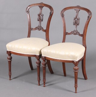 A pair of Victorian carved walnut slat back dining chairs with over stuffed seats, raised on turned supports 