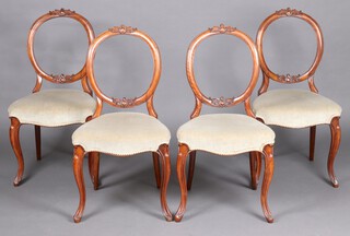 A set of 4 Victorian balloon back dining chairs with carved cresting rails and over stuffed seats, raised on cabriole supports 