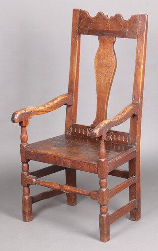 A 17th Century and later oak slat back open armchair with solid seat, raised on turned and block supports 