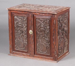 A Chinese heavily carved hardwood cabinet, fitted a drawer enclosed by a pair of panelled doors, carved dragons flowers and foliage 56cm h x 63cm w x 37cm d 
