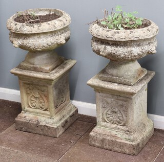 A pair of well weathered concrete garden  urns on Art Nouveau style pedestals 78cm h x 39cm diam. (in 4 sections) 