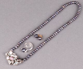 A string of purple pearls with silver pendant, a silver ring set a swivelling pearl and a pair of gold marked 585/15k pearl set earrings