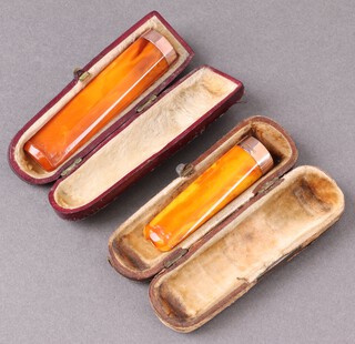 Two amber cigar holders with 9ct gold bands, cased 