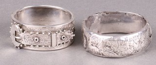 A hollow engraved silver bangle 28g (some dents) and an engraved bangle in the form of a buckle