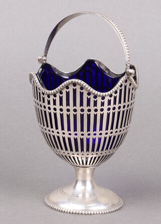 A Georgian style circular pierced silver sugar bowl with swing handle on a spreading foot, complete with blue glass liner, Chester 1911, marks rubbed, 130g 