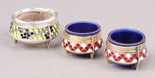 A pair of Hommet Russian Melchior enamelled and glass salt with blue plastic liners, together with a metal and enamelled salt marked Siommet 