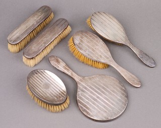 A 5 piece silver backed dressing table set comprising pair of hair brushes, pair of clothes brushes and a hand mirror, London 1926, together with a silver backed military hair brush Birmingham 1925 