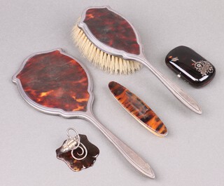 A two piece silver and tortoiseshell backed dressing table set with hand mirror and hair brush, Birmingham 1929, marks rubbed, a ditto bookmark, ditto purse and a nail buffer 