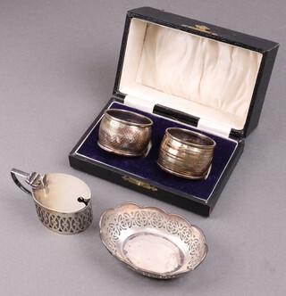 A pair of engine turned silver napkin rings Birmingham 1923, cased, an oval pierced silver dish Birmingham 1926, an oval pierced silver mustard pot (no liner) Birmingham 1891, 106g 