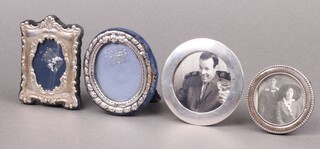 A circular easel photograph frame Birmingham 1903 2.5cm (some dents), an oval embossed silver ditto Birmingham 1985 8cm (some dents), an easel ditto marked 925 4cm and a circular white metal ditto 3cm 