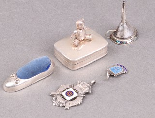 An Edwardian silver and enamelled watch chain medallion Birmingham 1911, a Sterling silver charm with armorial decoration, a 925 pill box the finial a seated bear, a 925 slipper pin cushion, 41g gross together with a metal perfume funnel 