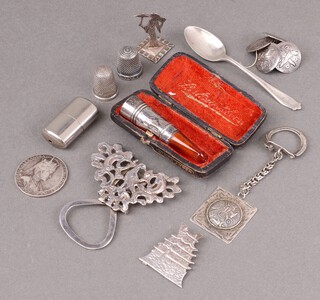 A silver and amber cheroot holder Birmingham 1907, cased, a silver coffee spoon, a 950 Sterling menu holder in the form of a pagoda, an 800 figure of a Geisha girl 3cm, 2 silver thimbles and a 925 Sterling key ring, weighable silver 36g together with a commemorative medallion, 5 metal buttons, a clip, etc 