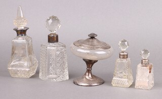 A silver and glass pedestal powder bowl Birmingham 1925 10cm (glass cracked, base misshapen), 3 square cut glass dressing table bottles with silver collars (dents to collars, 1 has a stuck stopper, 1 stopper chipped) and 1 other with silver collar 