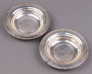 A pair of circular embossed white metal dishes decorated a ship, marked M/Y Stella Polaris B.D.S 8305 M.A.A.S.F, 9cm 
