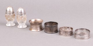 A pair of cut glass pepperettes with silver lids (dented), together with 4 napkin rings (2 misshapen) 59g