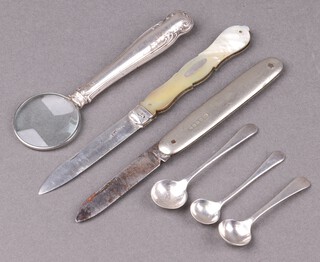 A Victorian silver bladed folding fruit knife with mother of pearl grip (marks rubbed), a silver handled magnifying glass, 3 silver salt spoons and a silver folding pocket knife with silver plated grip 