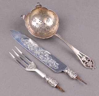 A Victorian silver knife and fork with engraved blade, Birmingham 1865, 41g together with a pierced silver tea strainer Sheffield 1938 39g 