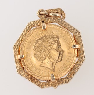 A gold half sovereign 2002 in an octagonal diamond and sapphire set pendant mount 