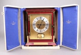 A Jaeger Le Coultre Atmos clock, serial number 938, having a gilt dial with silvered chapter ring, contained in a gilt and red lacquered case 27cm h x 22cm w x 14cm d, in original presentation case and with instruction booklet, there is a presentation plaque to the front 