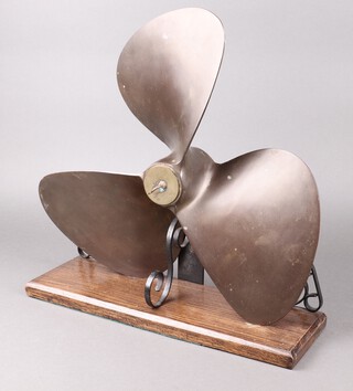 A bronze 3 bladed ships propellor mounted on a wrought iron and oak base 46m h x 48cm w x 14cm d 