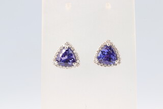 A pair of white gold testing as 14k tanzanite and diamond surround ear studs, the central tanzanites 3.6ct total, the diamonds 0.29ct, the diamonds colour I, clarity SI, with GEM Passport certificate, 4.3g gross
