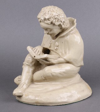 A German pottery figure of a boy seated reading a book, the base with paper label Handarbeit 24cm 