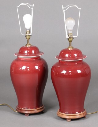 A pair of sang de boeuf style table lamps in the form of lidded urns 46cm on wooden hardwood bases