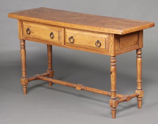 A light hardwood side table fitted 2 drawers with iron ring drop handles raised on turned supports 76cm h x 129cm w x 45cm d 