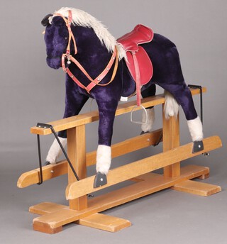 A Pegasus rocking horse, in purple fabric with red saddle and reins, raised on an oak cruciform base 118cm h x 138cm w x 60cm d 