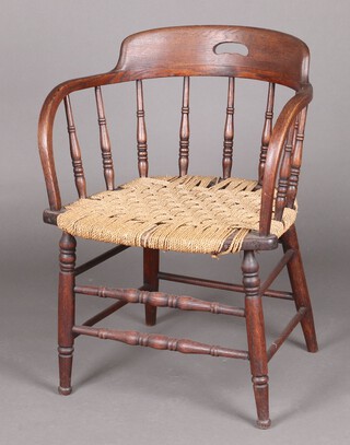 An elm tub back chair with spindle decoration and woven seat, raised on turned supports
