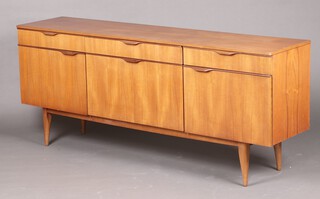 A mid-century teak sideboard fitted 3 drawers above a cocktail unit with fall front, flanked by cupboards enclosed by panelled doors, raised on outswept supports 76cm h x 182cm w x 42cm d 