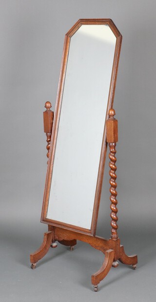 A 1930's shaped cheval mirror contained in an oak frame on spiral turned supports 156cm h x 40cm w x 54cm d (silvering to the mirror is showing signs of deterioration) 