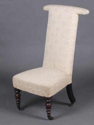 A Victorian prie dieu chair upholstered in cream material and raised on turned supports