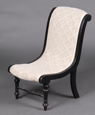 A Victorian slipper shaped ebonised nursing chair upholstered in white material on turned supports with stretcher 