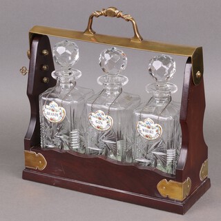Three cut glass decanters contained in an associated tantalus with Coalport porcelain decanter labels - Brandy, Gin, Whisky 