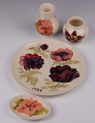 A Walter Moorcroft 1985 anemone year plate boxed 22cm diam, a Moorcroft cream ground Hibiscus stub vase 11cm, a ditto Moorcroft Hibiscus oval dish 11cm (chipped) and a Moorcroft cream ground Columbine stub shaped vase 7cm, 