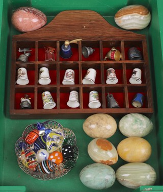 A collection of 18 thimbles contained in a display case, 8 polished eggs and a collection of Murano glass style sweets 