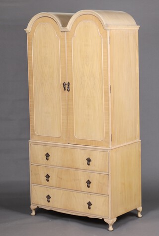 A 1950's Queen Anne style bleached walnut double dome topped wardrobe, fitted a hanging rail enclosed by arched panelled doors, the base fitted 3 drawers, raised on cabriole supports 190cm h x 91cm w x 52cm d 