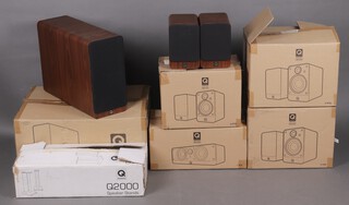 A set of Q Acoustics Home Cinema Speakers to include two pairs of 2020 speakers, pair of 2010 bookshelf speakers, a 2070S base sub woofer and a 2000C centre speaker all in brown walnut and a pair of QA 2110 black speaker stands 