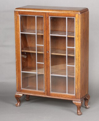 A 1930's oak display cabinet fitted shelves enclosed by lead glazed panelled doors, raised on cabriole supports 109cm h x 75cm w x 25cm d (water and contact marks in places)