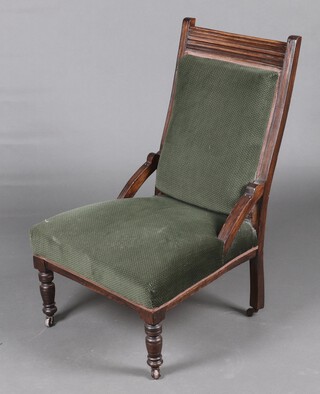 An Edwardian carved mahogany nursing chair, the seat and back upholstered in green material, raised on turned supports 