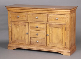 An oak dresser/sideboard fitted 3 long and 3 short drawers flanked by a pair of cupboards, raised on a platform base 92cm high x 142cm w x 44cm d 