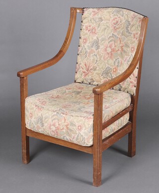 A 1930's oak open arm chair, the seat and back upholstered in tapestry material 